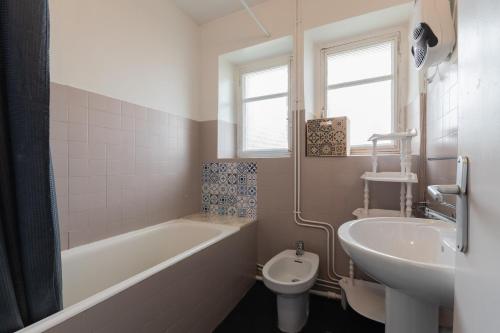 a bathroom with a tub and a toilet and a sink at La Maison Du Soleil L'aulhère in Oloron-Sainte-Marie