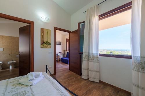 a bedroom with a bed and a large window at Casa Mirto con piscina e vista mare in Aglientu