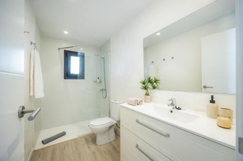 a bathroom with a sink and a toilet and a mirror at White suites in Cala d´Or