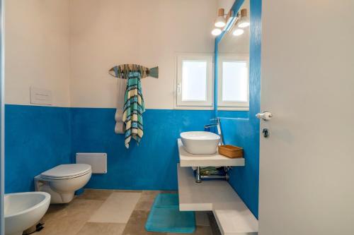 a blue bathroom with a toilet and a sink at Agrumeto sul mare in Ostuni