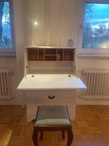 a desk with a stool in a room with two windows at Oberneulander Gästehaus in Bremen