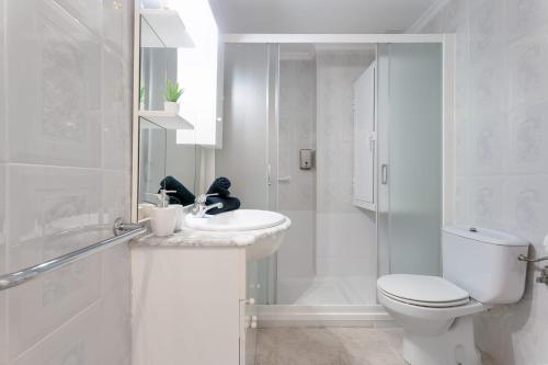 a white bathroom with a toilet and a sink at Sueño in La Mata
