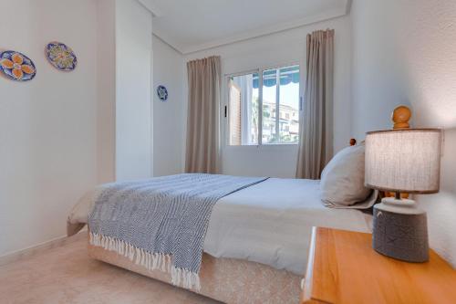 a white bedroom with a bed and a window at Sueño in La Mata