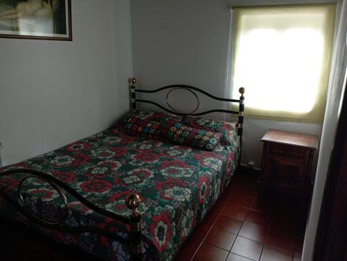 a bedroom with a bed with a quilt and a window at Refúgio da Montanha in Sobral