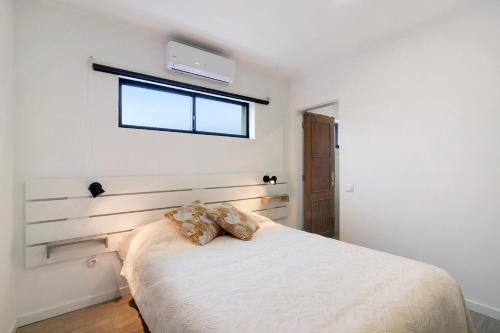 a white bedroom with a bed with a window at Apartamento nº2 - Seashel in Moncarapacho