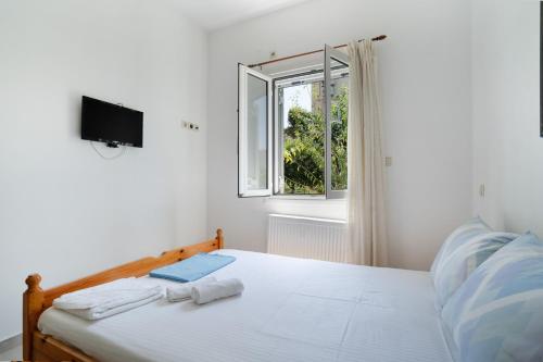 a white bedroom with a bed and a window at Elia home kanali in Kanali
