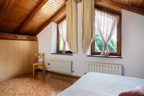a bedroom with a bed and two windows and a chair at Residence Bonetti in Rabbi