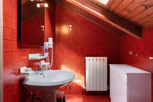 a red tiled bathroom with a sink and a mirror at Residence Bonetti in Rabbi