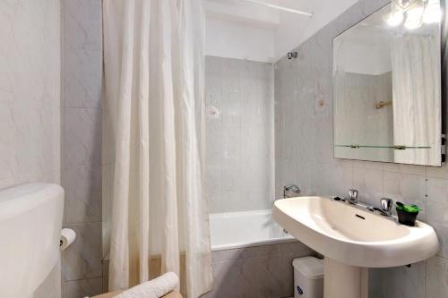 a white bathroom with a sink and a shower curtain at Beachfront Apartment T2 in Quarteira