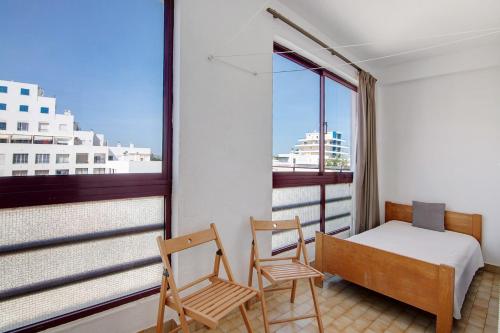 a bedroom with a bed and two chairs and a window at Beachfront Apartment T2 in Quarteira