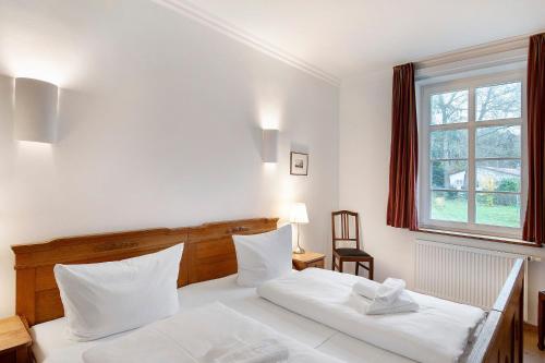 a bedroom with a white bed and a window at Gut Rattelvitz - Parterre Ost in Gingst