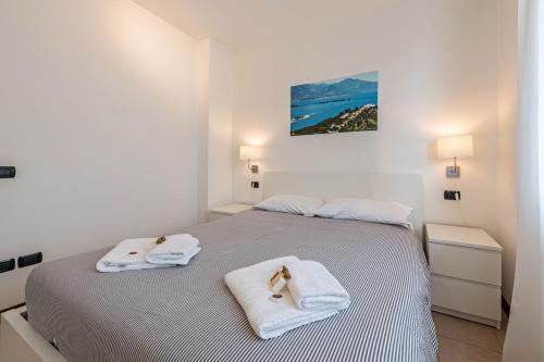 a white bedroom with two towels on a bed at Villa Bornico Marisa in Toscolano Maderno