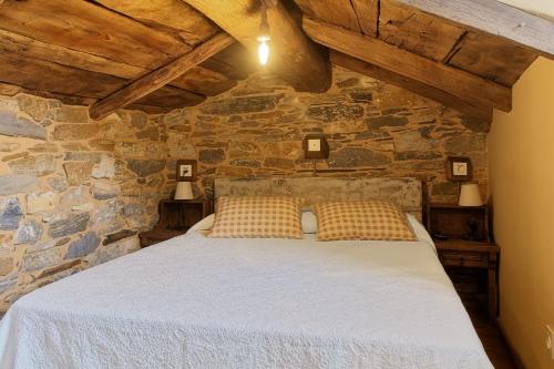 a bedroom with a bed in a stone wall at Miradoiro do Courel - Millares in Campelo
