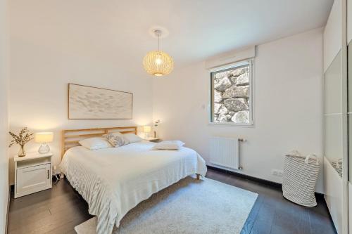 a white bedroom with a bed and a window at Les Terrasses de la Palud in Landéda