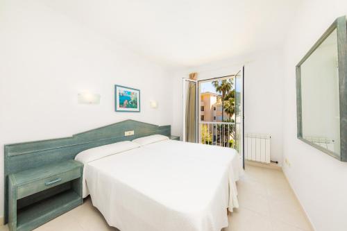 a white bedroom with a bed and a mirror at Oro del Mar iv apartamento 05 in Canyamel