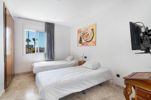 a bedroom with two beds and a tv and a window at Playa Graciosa in Arona