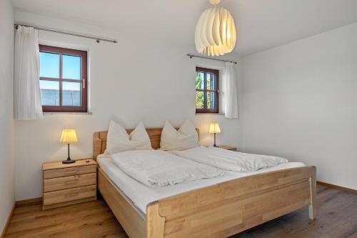 a bedroom with a bed with white sheets and two windows at Wohnung Untersbergblick in Freilassing