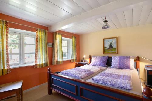a bedroom with a bed and two windows at Friesisches Reetdachferienhaus in Bordelum