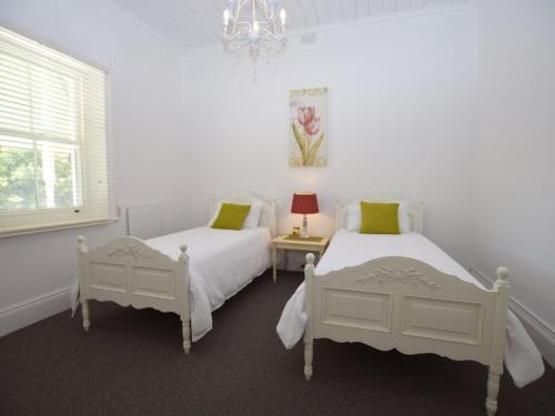 a white bedroom with two beds and a window at The Provincial in Minlaton