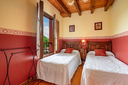 two beds in a room with red walls at Lolo in Villaviciosa