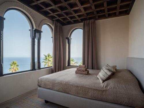 a bedroom with a bed with windows and the ocean at Villa Rocca in La Herradura