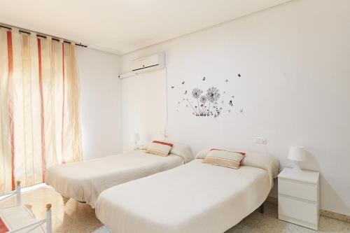 two beds in a room with white walls at Casa López in Baena