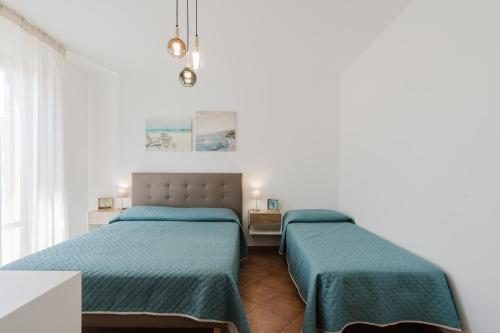 two beds in a white room with green sheets at Kairos San Vito Lo Capo in San Vito lo Capo