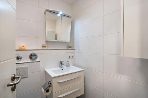 a white bathroom with a sink and a mirror at Zentrale Ferienwohnung mit Balkon in Bad Liebenzell