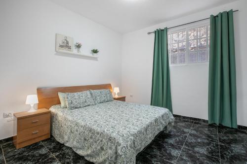 a bedroom with a bed and a window with green curtains at Momento florida in San Andrés