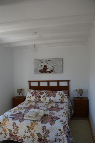 a bedroom with a bed with a floral comforter at O Bolaño Apto 3 in Villarino de Conso