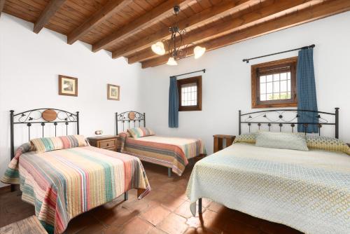 two beds in a room with white walls and wooden ceilings at Mansión Piedras Blancas in Colmenar