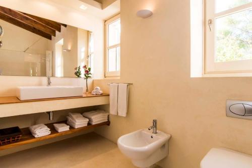 a white bathroom with a sink and a mirror at Can Bossa in Capdepera