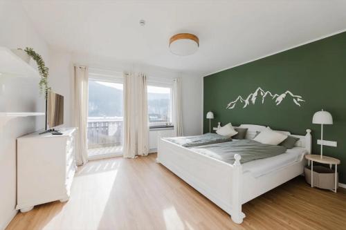 a bedroom with a white bed and a green wall at Ferienwohnung Waldzauber Lennestadt in Lennestadt