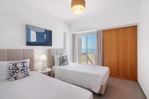a bedroom with two beds and a window at Moderno e acolhedor com vista mar in Quarteira