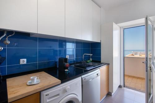 a kitchen with a sink and blue tiles at Moderno e acolhedor com vista mar in Quarteira