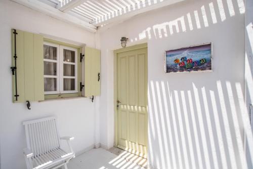 a white room with a yellow door and a chair at Green Retreats 5 Paros in Isterni