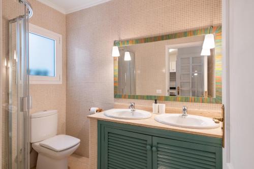 a bathroom with two sinks and a toilet and a mirror at Apartamento Cipreses in Puerto del Carmen