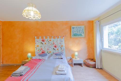 a bedroom with a bed with orange walls and a window at Maison Sébastien in Saint-Pierre-de-Côle