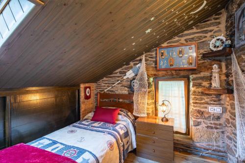 a bedroom with a bed and a stone wall at Casa Da Puza in Forcarei
