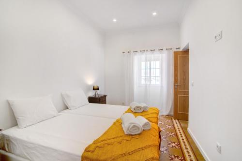 a bedroom with a large white bed with towels on it at Quinta Alegre Tavira Moderno T2 in Luz de Tavira