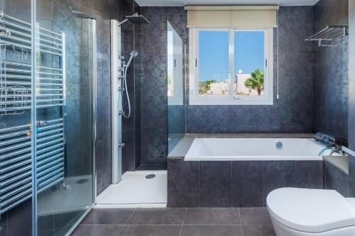 a bathroom with a tub and a toilet and a window at Ático Las Palmeras in Cala Millor