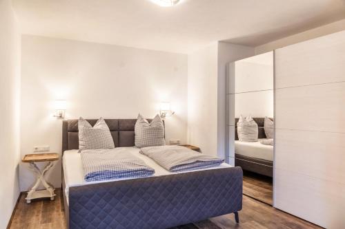 a bedroom with a blue bed and a mirror at Ferienwohnung Zugspitze in Ehrwald