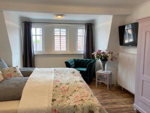a bedroom with a bed and a chair and windows at Ferienwohnung Rahel in Münsingen