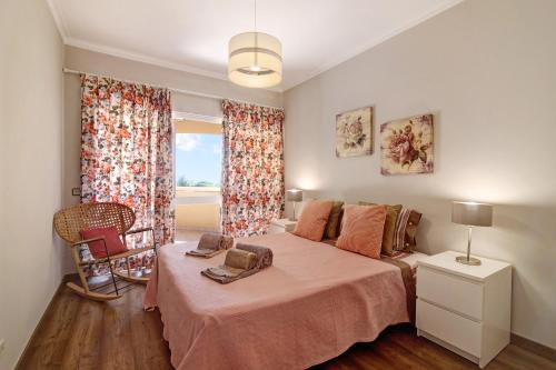 a bedroom with a bed with a pink blanket and a window at Palmeira Galé in Galé