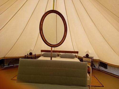 a bed with a mirror in a tent at Glamping C Selva Tenda Ciliegio in Piano Porlezza