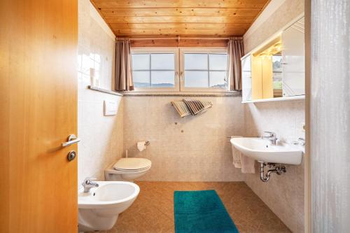 a bathroom with two sinks and a toilet and a window at Lingerhof Alpenrose in Meltina