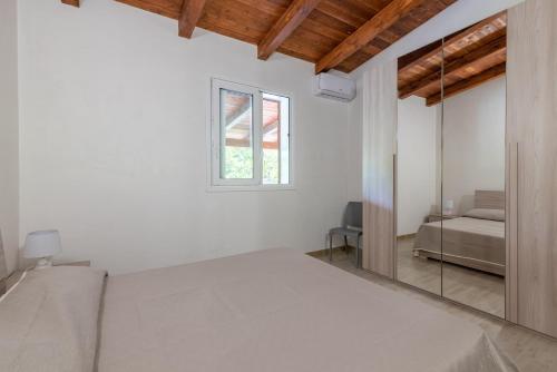 a white bedroom with a bed and a mirror at Villa Lorenzo in Avola