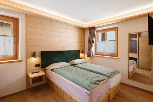 a bedroom with a bed and two windows at Alpi Flo Chalet in Livigno