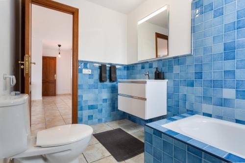 a blue tiled bathroom with a toilet and a sink at El Pico in La Santa