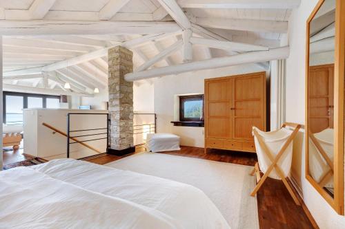 a bedroom with a white bed and a stone pillar at Haus mit tollem See -und Bergblick in Gargnano